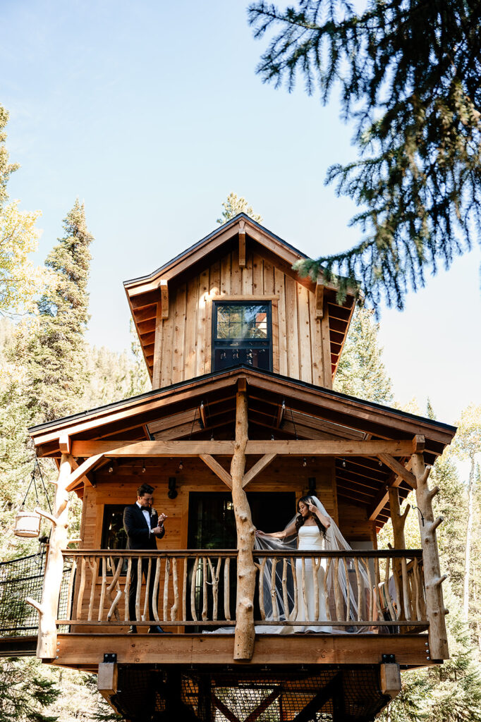 a bride and groom standing on a porch of a treehouse AirBnB wedding venue
