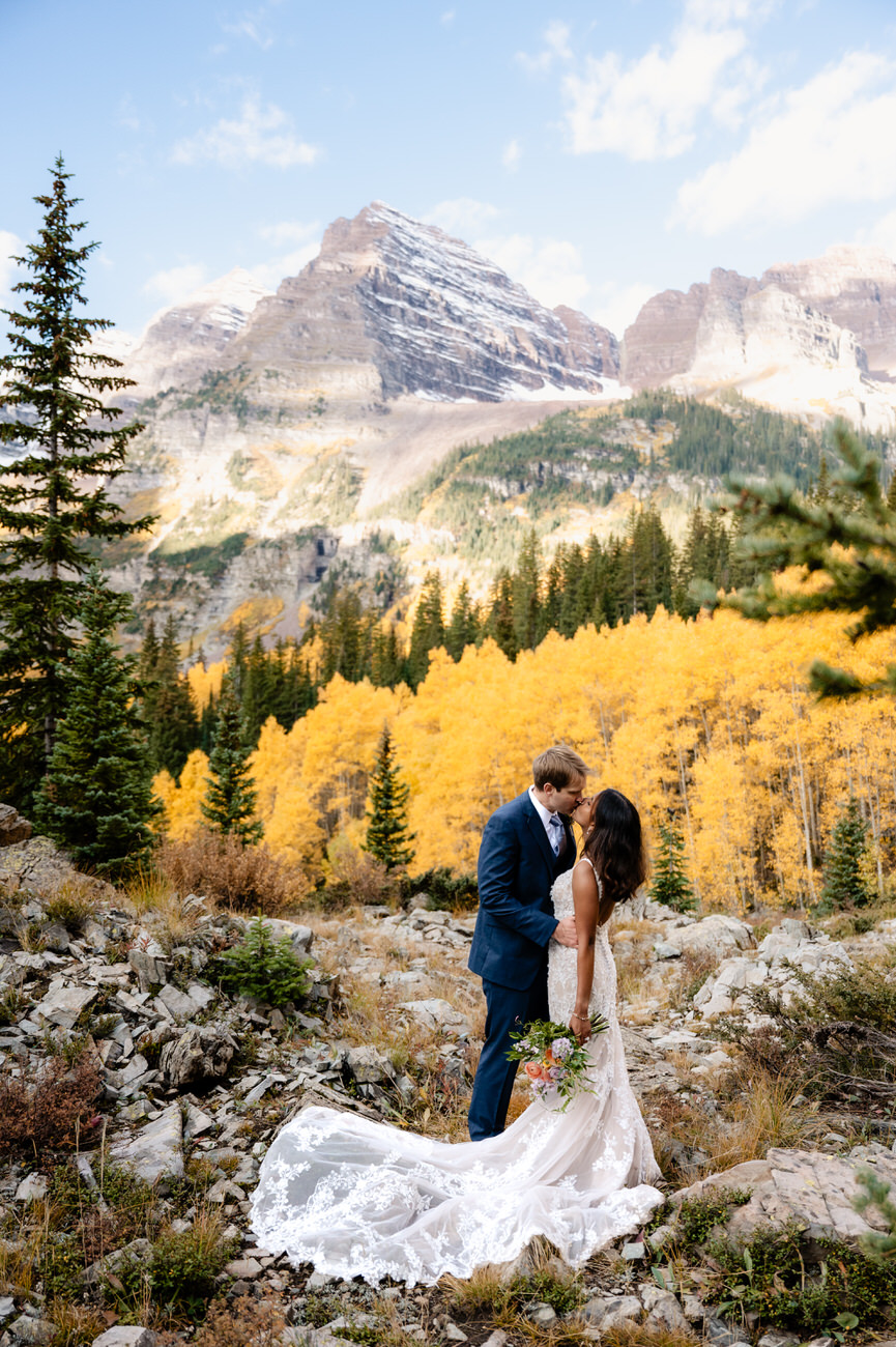 a man and woman kissing in front of mountains