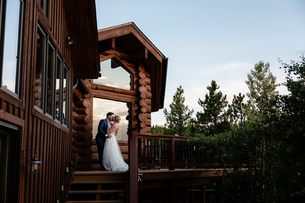 a bride and groom kissing on a porch of a log cabin VRBO wedding venue