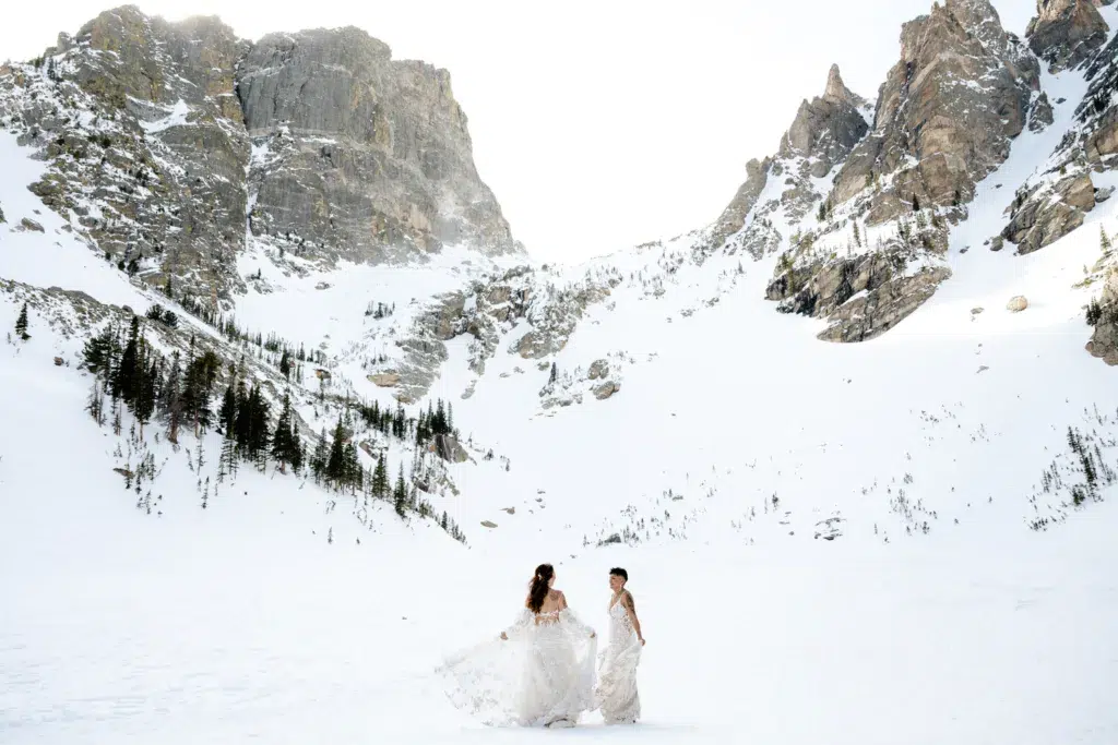 two brides dancing in wedding dresses in the winter in Rocky Mountain National Park in Colorado